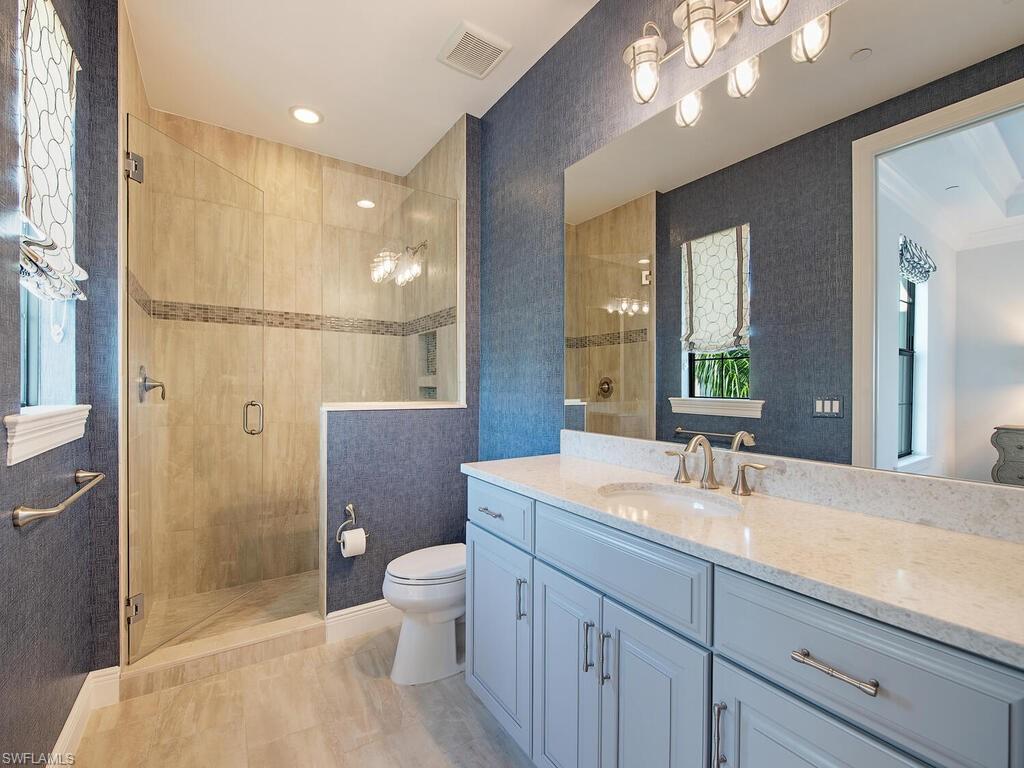 16444 Carrara Way, Unit 7301 Naples, FL 34110 - Photo 15 of 22 a bathroom with a double vanity sink toilet and shower