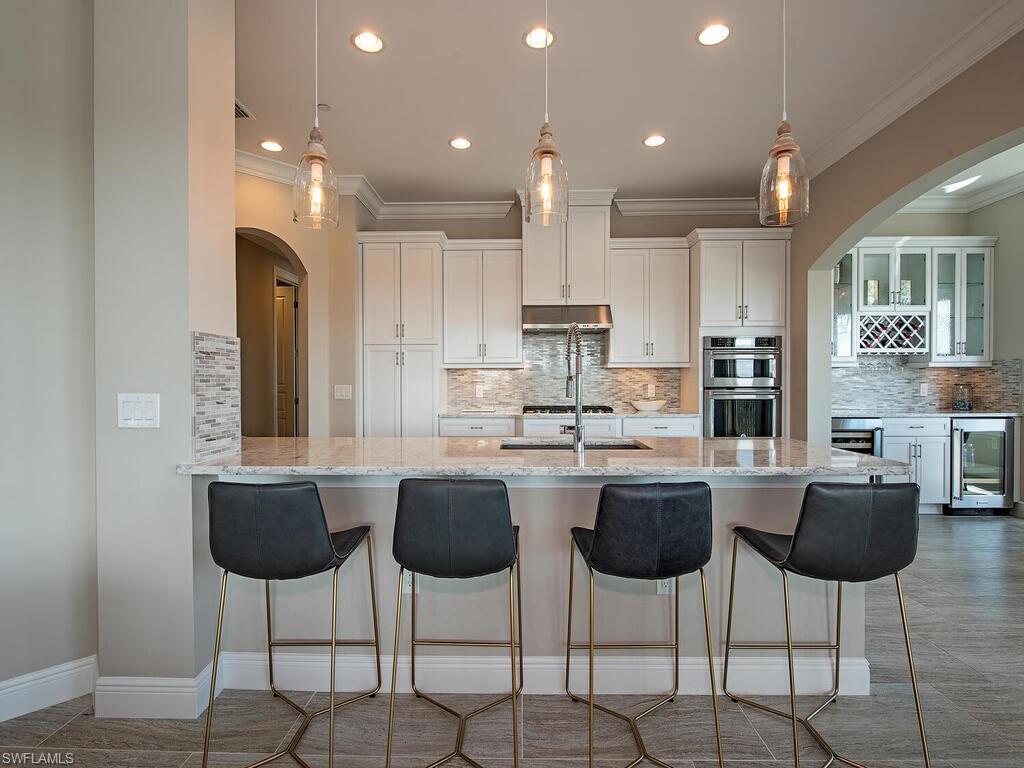 16444 Carrara Way, Unit 7301 Naples, FL 34110 - Photo 4 of 22 a kitchen with stainless steel appliances kitchen island granite countertop a table and chairs