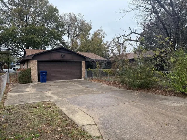a backyard of a house with large trees and brick wall