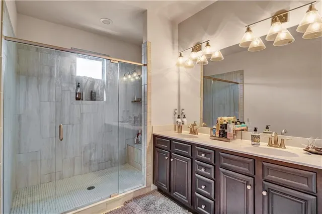 a bathroom with a double vanity sink mirror and shower