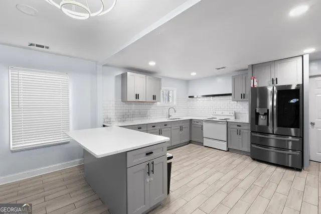 a kitchen with stainless steel appliances kitchen island granite countertop a refrigerator and a sink