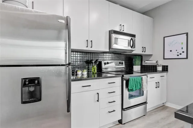 a kitchen with kitchen island white cabinets and stainless steel appliances