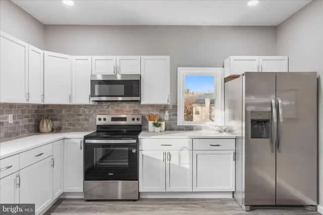 a kitchen with white cabinets and stainless steel appliances