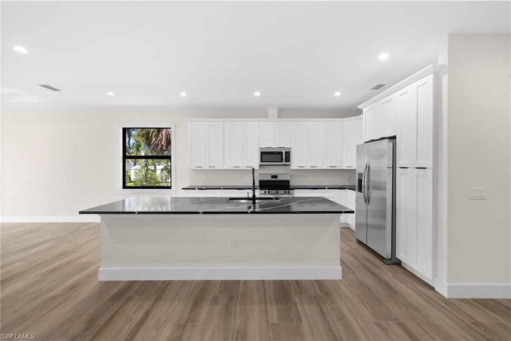 3049 Pine Tree Drive Naples, FL 34112 - Photo 18 of 38 a large kitchen with stainless steel appliances granite countertop a lot of counter space and wooden floor