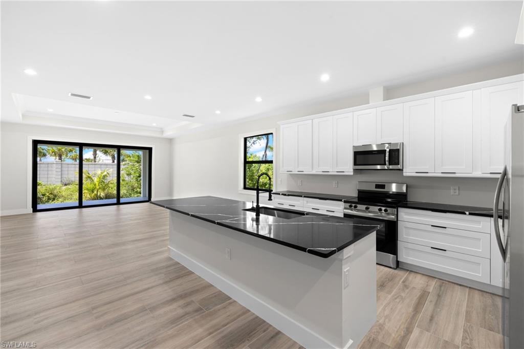 3049 Pine Tree Drive Naples, FL 34112 - Photo 20 of 38 a kitchen with stainless steel appliances granite countertop a stove a sink and a refrigerator
