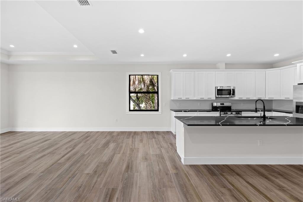3049 Pine Tree Drive Naples, FL 34112 - Photo 24 of 38 a large white kitchen with wooden floors and stainless steel appliances