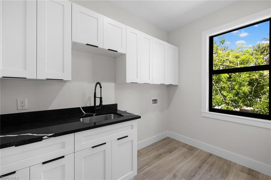 3049 Pine Tree Drive Naples, FL 34112 - Photo 32 of 38 a kitchen with granite countertop white cabinets and black appliances