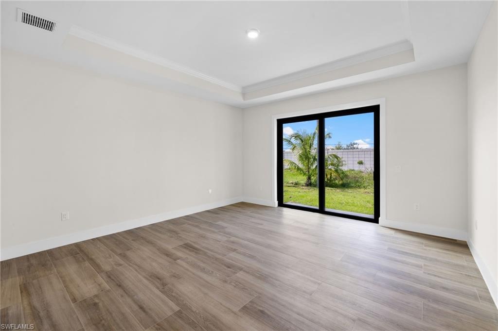 3049 Pine Tree Drive Naples, FL 34112 - Photo 6 of 38 a view of an empty room with wooden floor and a window