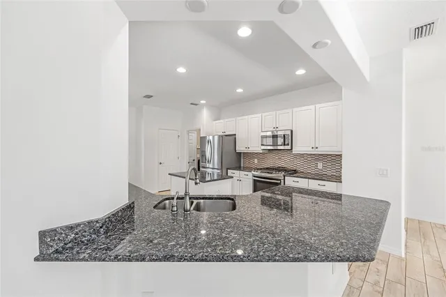 a kitchen with stainless steel appliances granite countertop a sink stove and refrigerator