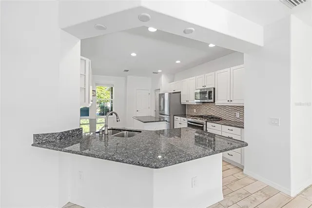 a kitchen with kitchen island granite countertop a sink a counter top space and cabinets