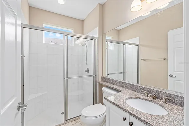 a bathroom with a granite countertop sink toilet and shower