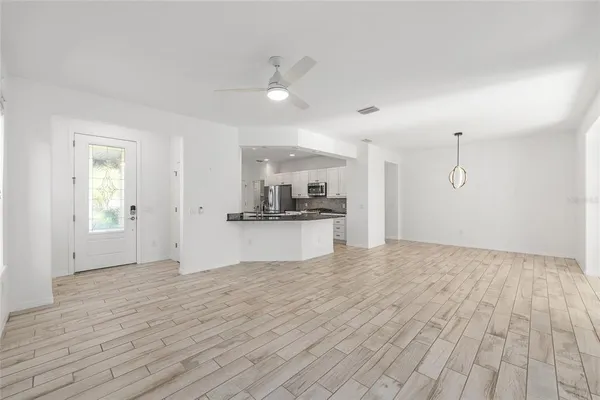 a view of an empty room with kitchen and window