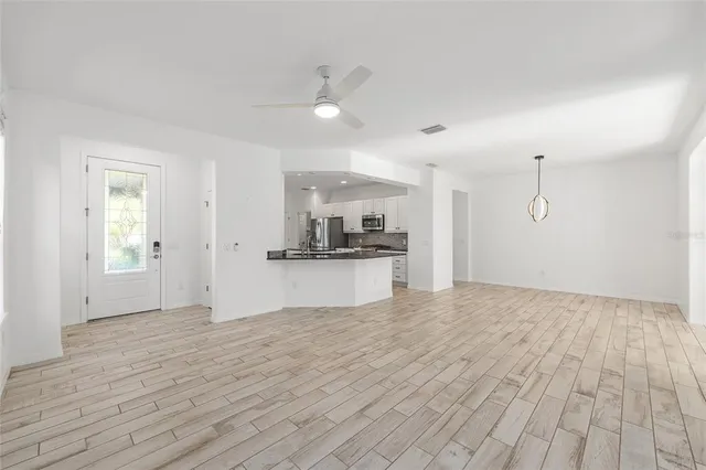a view of an empty room with kitchen and window