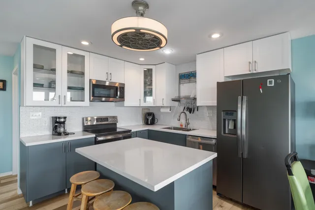 a kitchen with stainless steel appliances kitchen island a table chairs in it and wooden floors