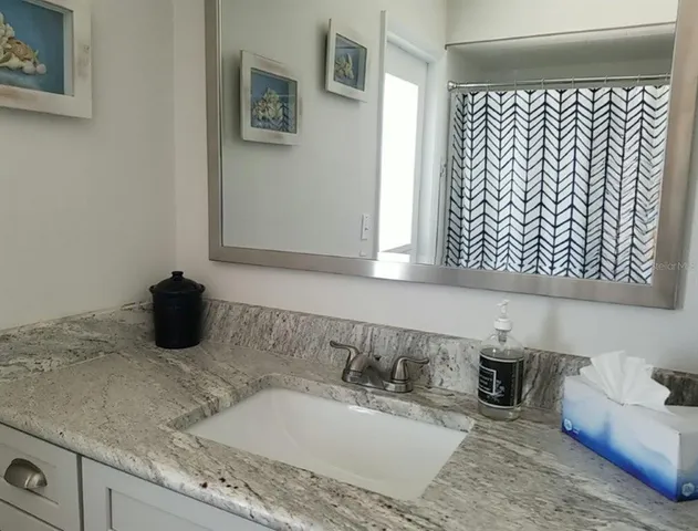 a bathroom with a granite countertop sink and a mirror