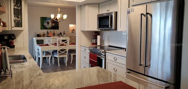 a kitchen with stainless steel appliances granite countertop a refrigerator and a stove top oven