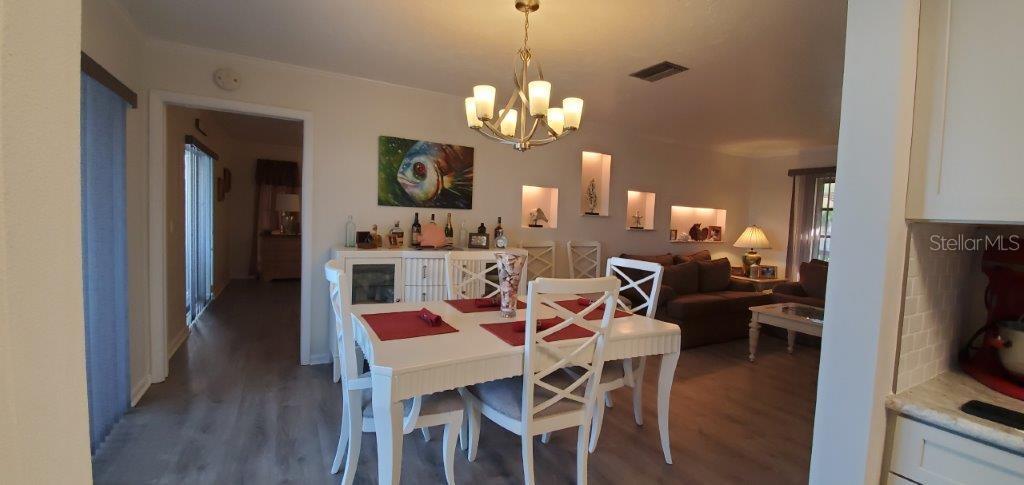 2122 Cassino Court Punta Gorda, FL 33950 - Photo 6 of 25 a dining room with wooden floor a chandelier a wooden table and chairs