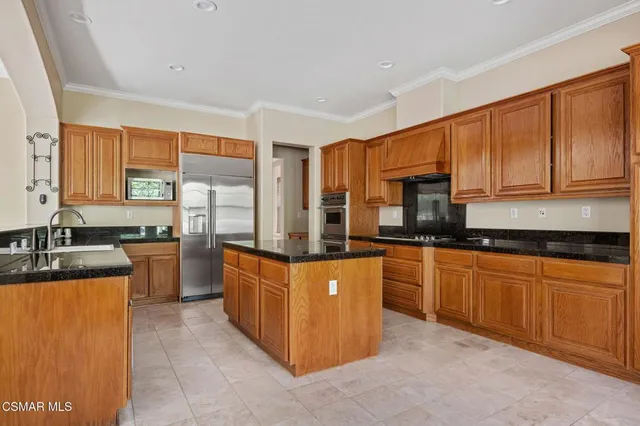 a kitchen with stainless steel appliances granite countertop wooden cabinets a sink a stove a refrigerator with grey cabinets and wooden floor