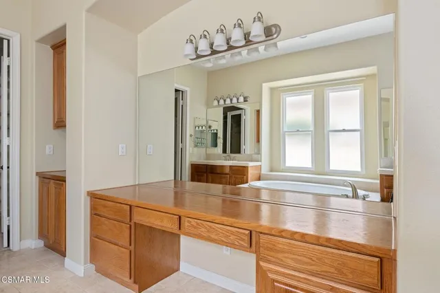 a bathroom with a granite countertop sink a mirror a bathtub and next to a window