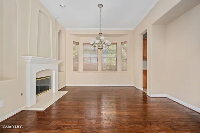 a view of an empty room with wooden floor fireplace and a window