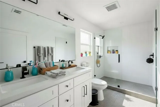 a bathroom with a double vanity sink toilet and shower