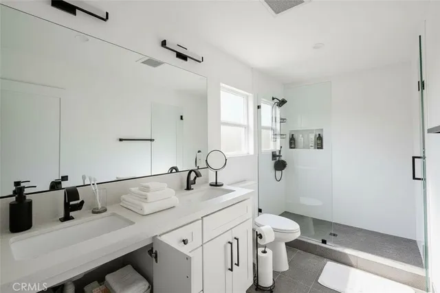 a bathroom with a granite countertop sink a toilet and shower