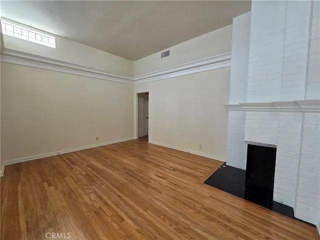 a view of empty room with wooden floor and fireplace