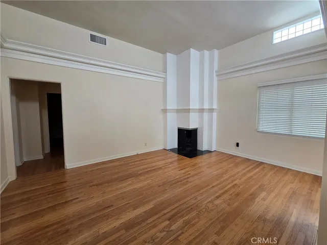 a view of empty room with wooden floor and fireplace