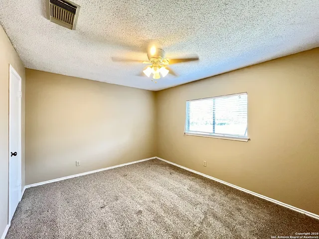 an empty room with a chandelier fan and a window