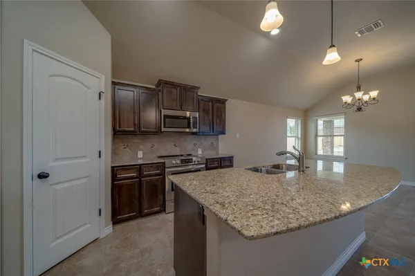 a kitchen with kitchen island granite countertop a sink stove and refrigerator