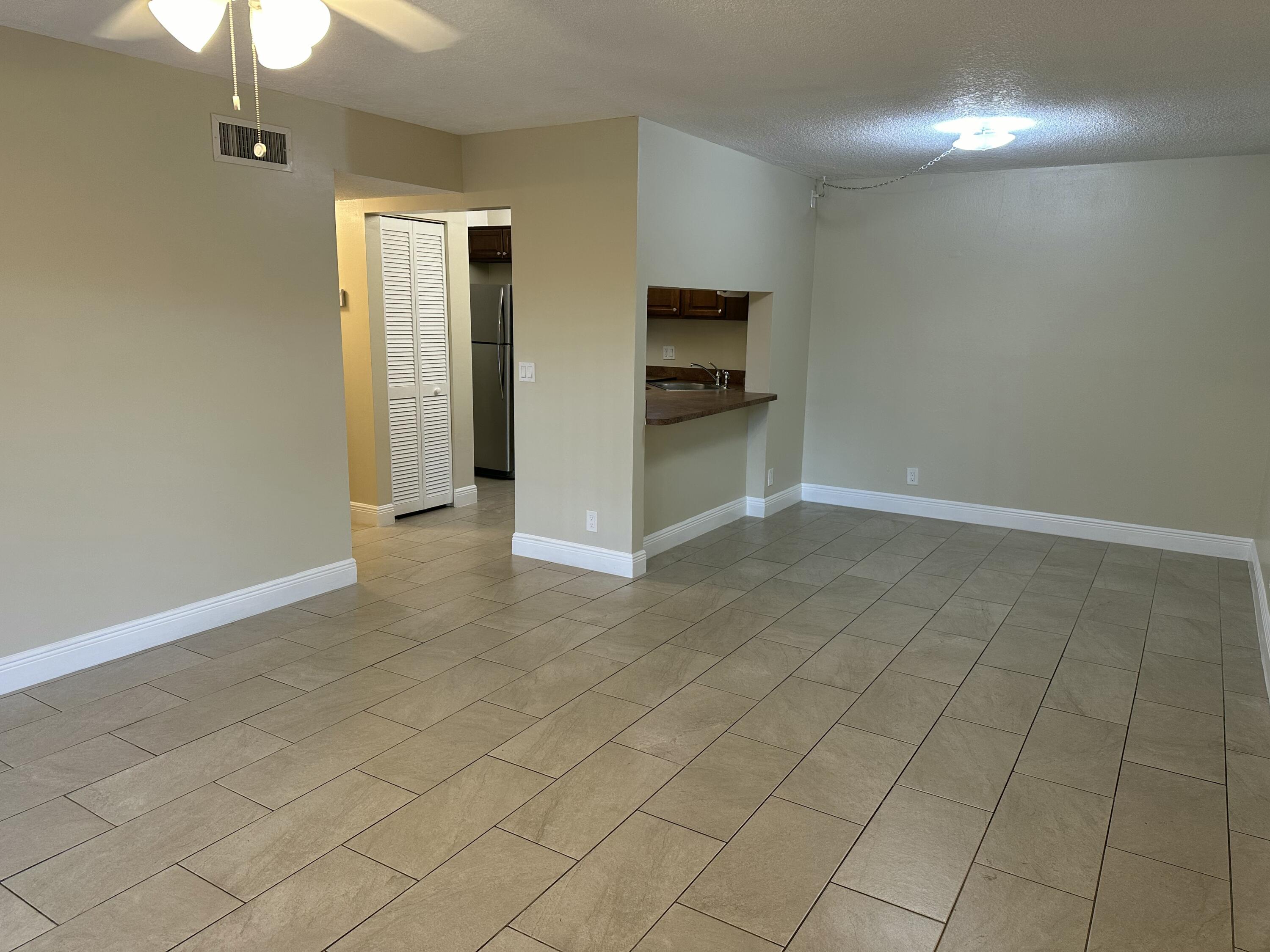 a view of a refrigerator in kitchen and an empty room