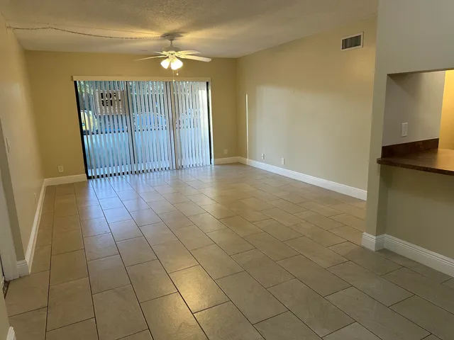 a view of an empty room with window and chandelier fan