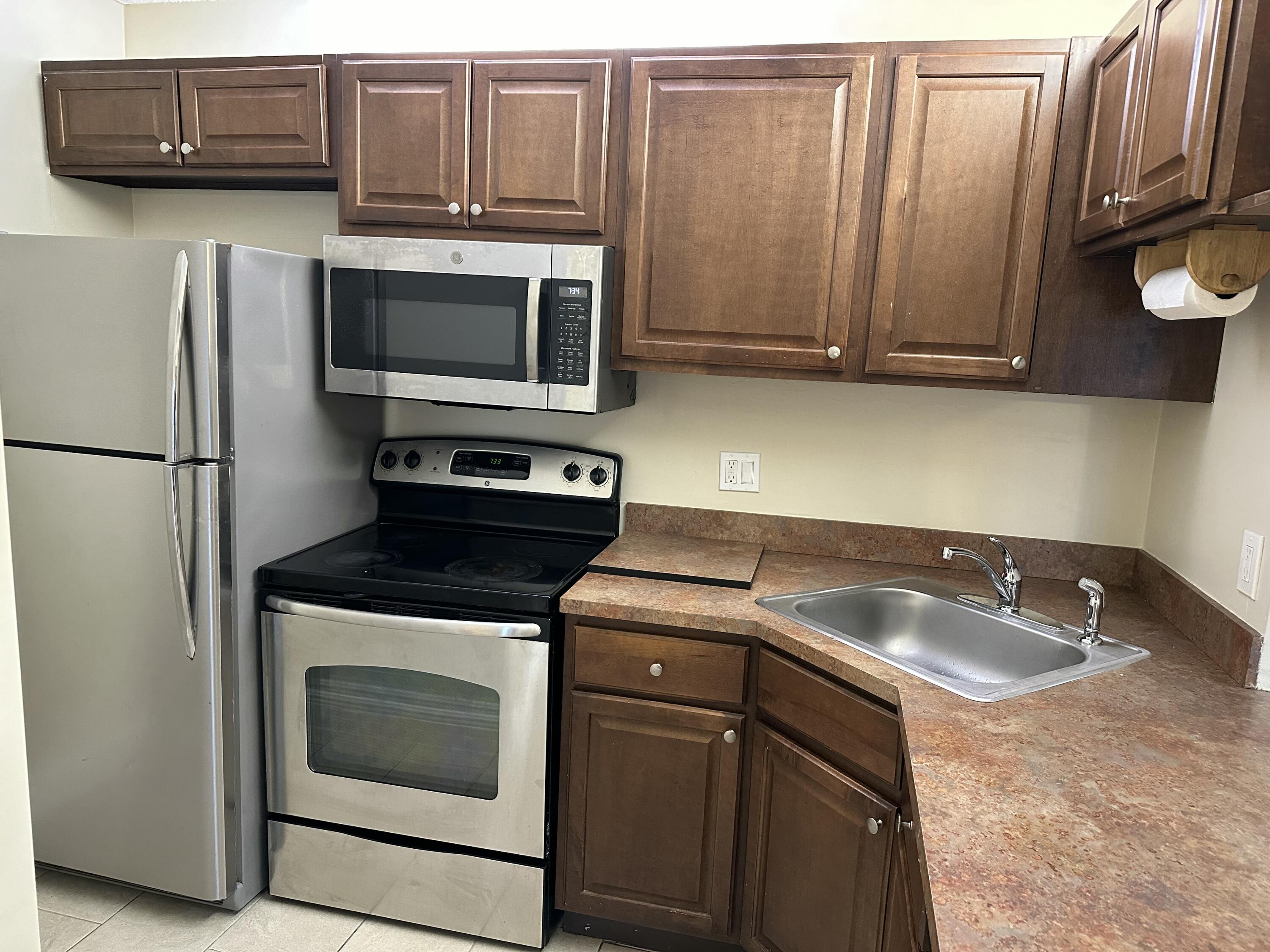 202 Foxtail Drive, Unit A1 Greenacres, FL 33415 - Photo 3 of 10 a kitchen with granite countertop a sink stove and microwave