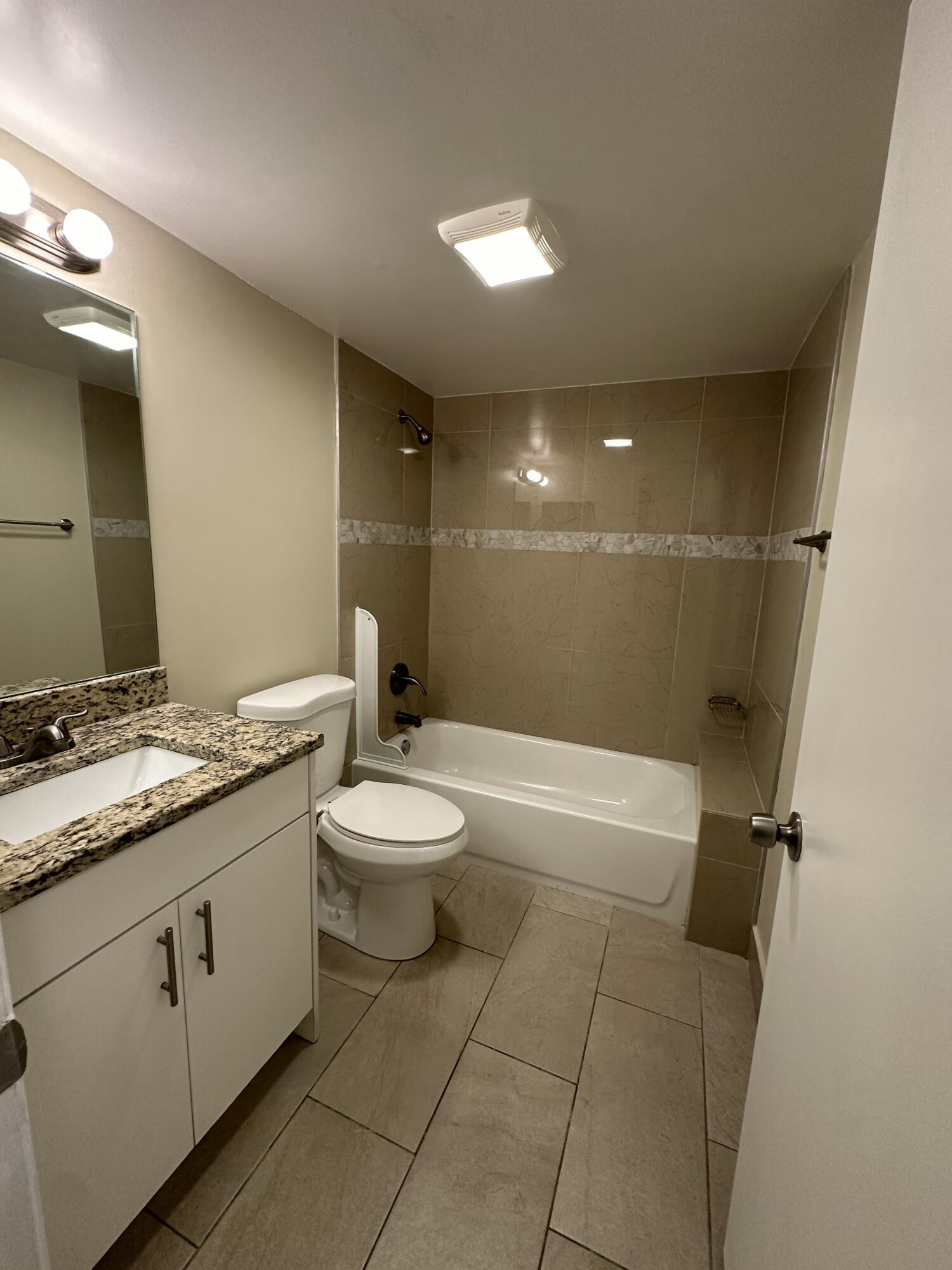 202 Foxtail Drive, Unit A1 Greenacres, FL 33415 - Photo 6 of 10 a bathroom with a granite countertop sink a toilet and a mirror