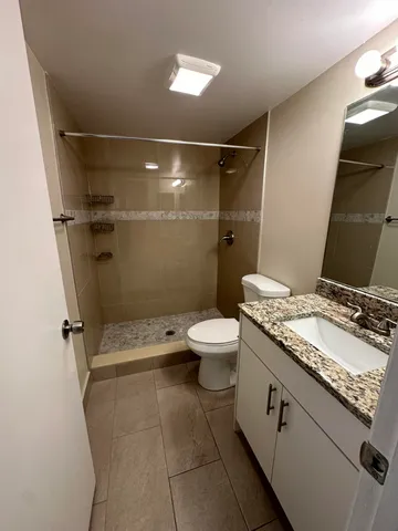 a bathroom with a granite countertop sink toilet and shower