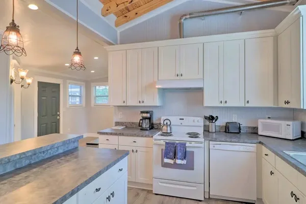a kitchen with kitchen island granite countertop white cabinets and white appliances