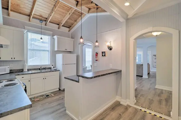 a kitchen with granite countertop a refrigerator and white cabinets