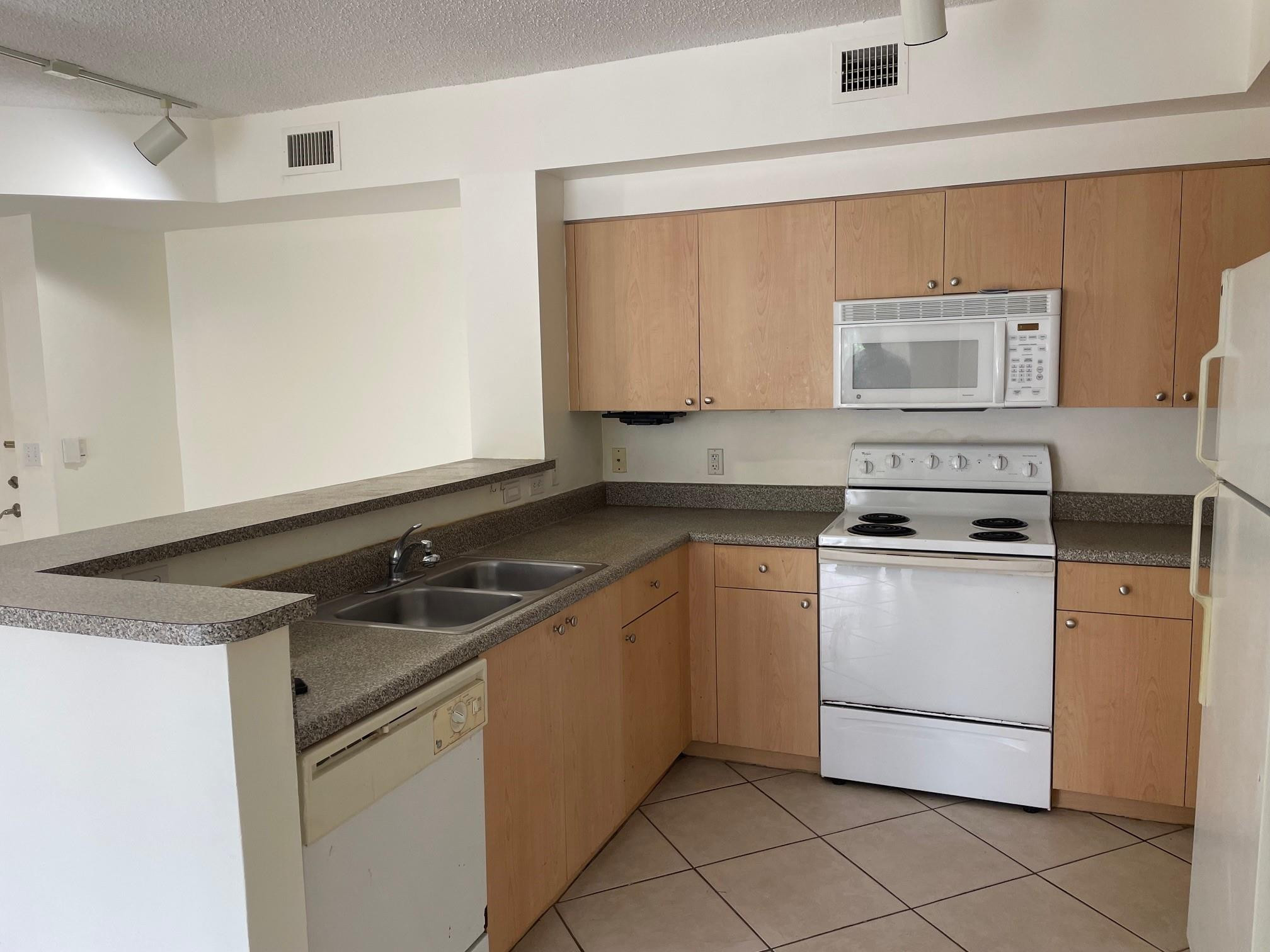 8010 North Nob Hill Road, Unit 205 Tamarac, FL 33321 - Photo 3 of 14 a kitchen with a sink stove and cabinets