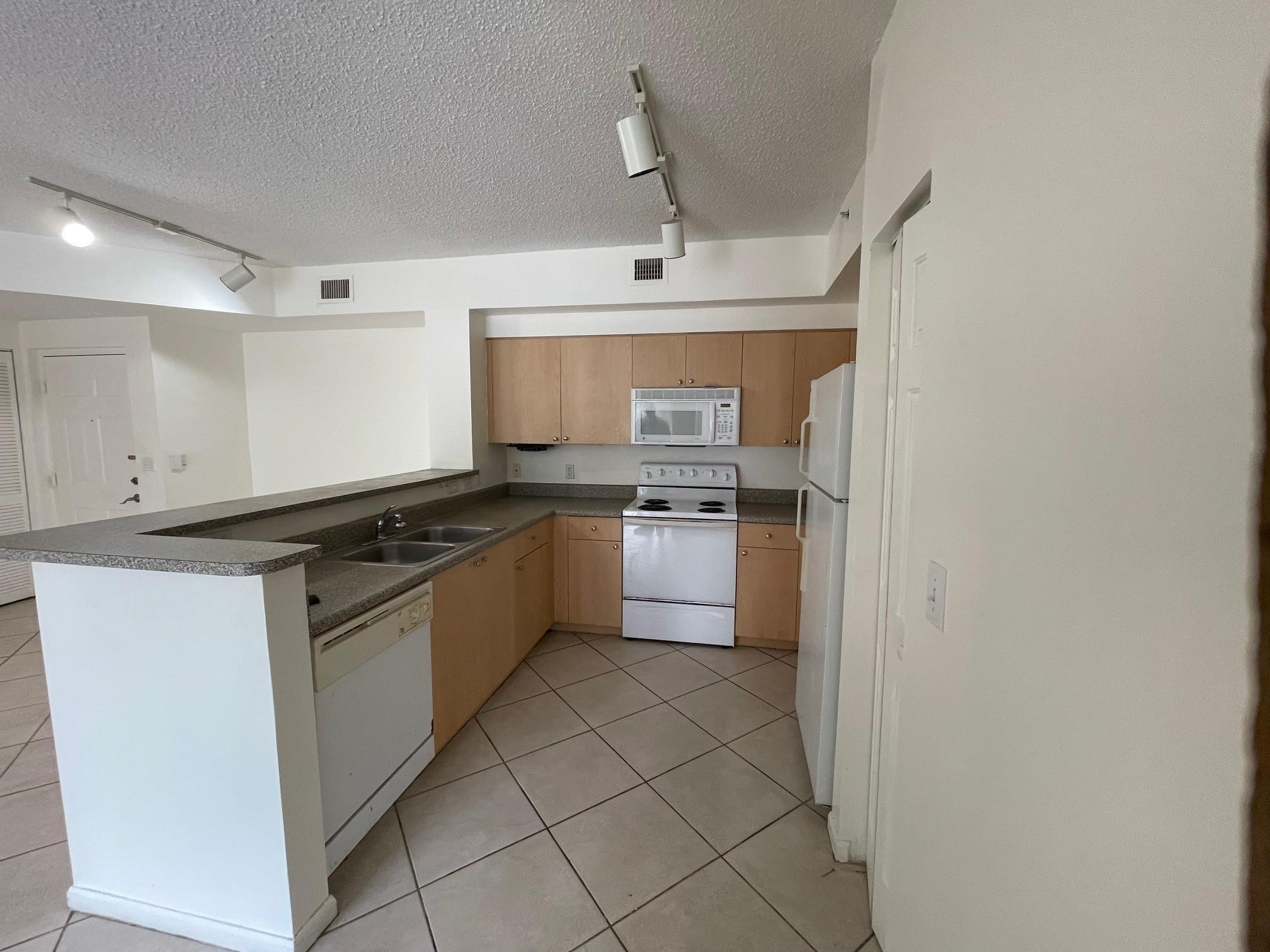 8010 North Nob Hill Road, Unit 205 Tamarac, FL 33321 - Photo 4 of 14 a kitchen with stainless steel appliances granite countertop a sink and cabinets