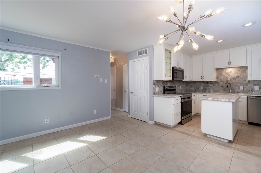 6232 Weber Road Corpus Christi, TX 78413 - Photo 11 of 23 a kitchen with kitchen island granite countertop a stove a sink a refrigerator and white cabinets with wooden floor