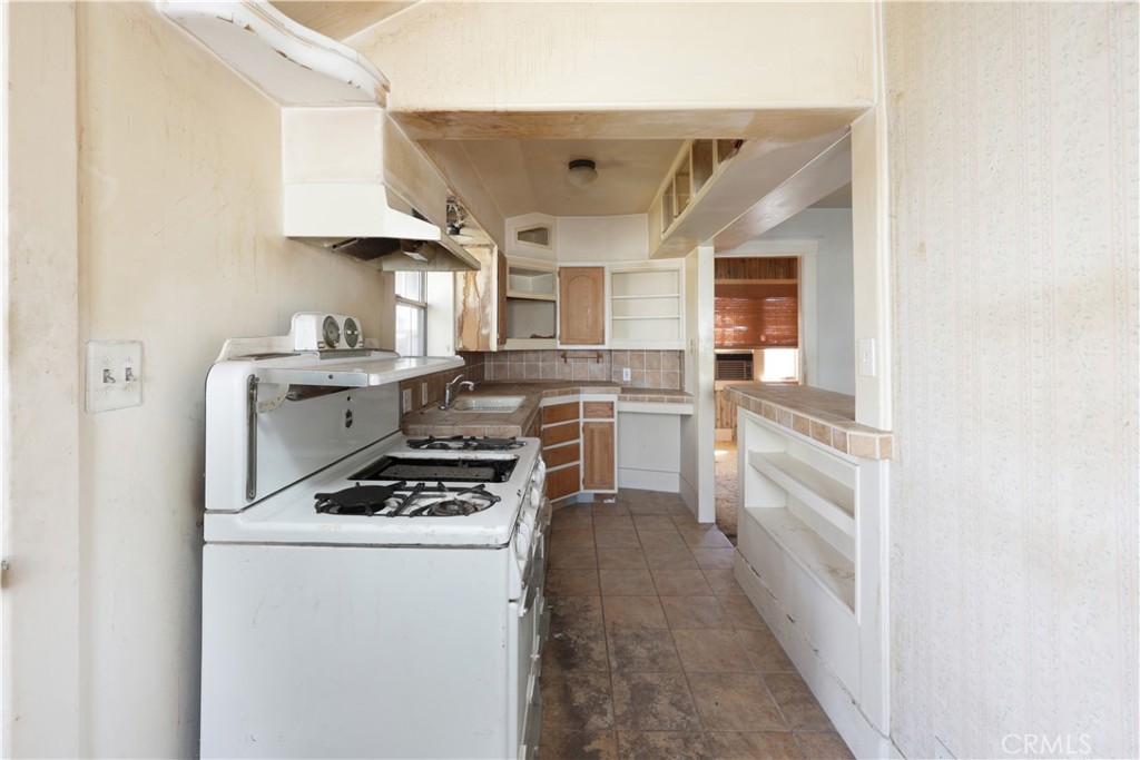 9211 Walnut Street Bellflower, CA 90706 - Photo 8 of 26 a kitchen with stainless steel appliances a stove a sink and white cabinets
