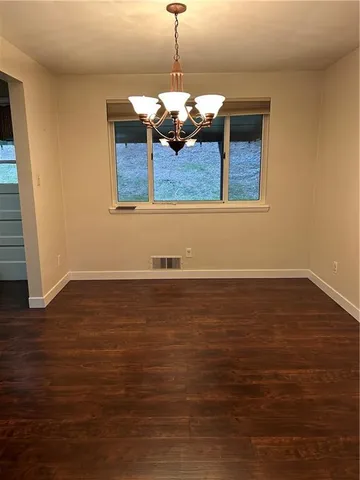 a view of kitchen and empty room with wooden floor