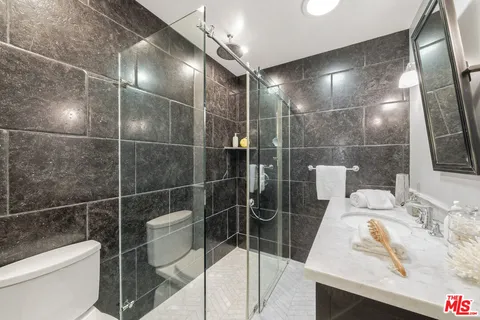 a bathroom with a granite countertop sink a toilet and shower