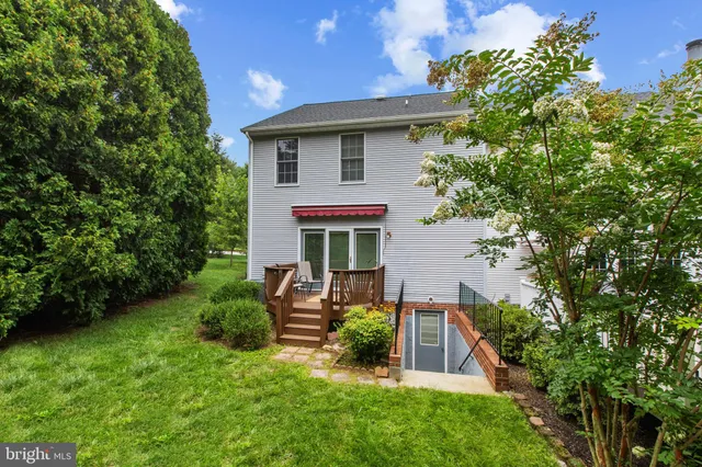 a view of backyard of house with wooden deck and seating