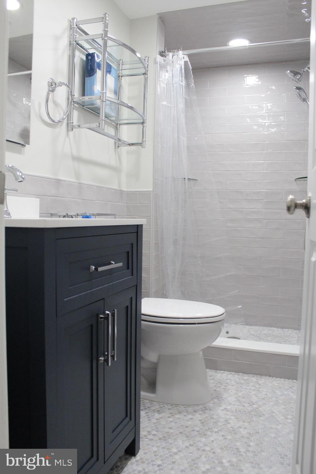 7703 Newcastle Drive Annandale, VA 22003 - Photo 2 of 12 a bathroom with a granite countertop sink a toilet and shower