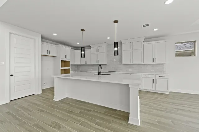 a kitchen with stainless steel appliances granite countertop a sink a stove and a wooden floors