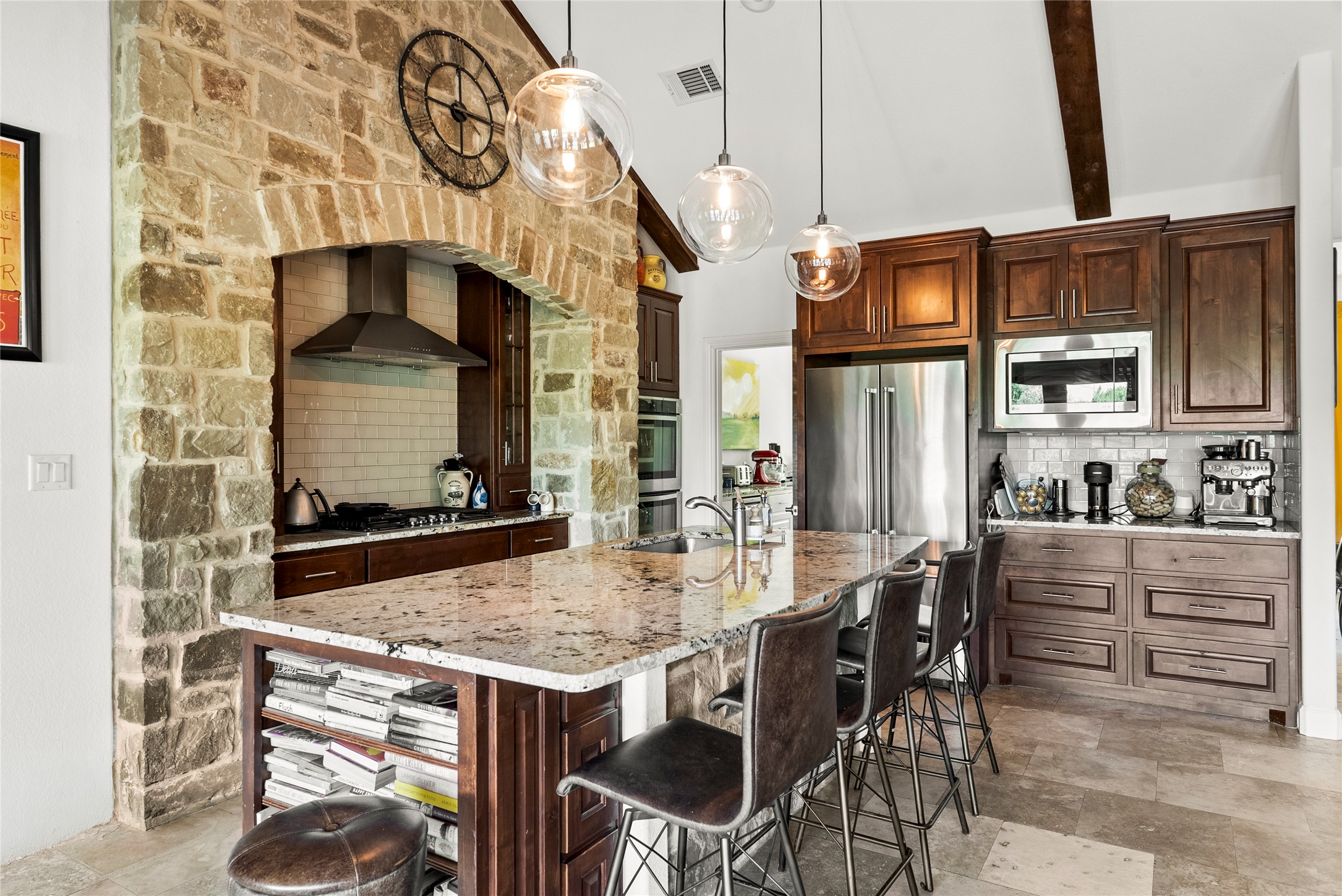 23224 Nameless Road Leander, TX 78641 - Photo 11 of 23 A well-appointed kitchen features a large granite-topped island with seating, alongside rich wood cabinetry and stainless steel appliances.