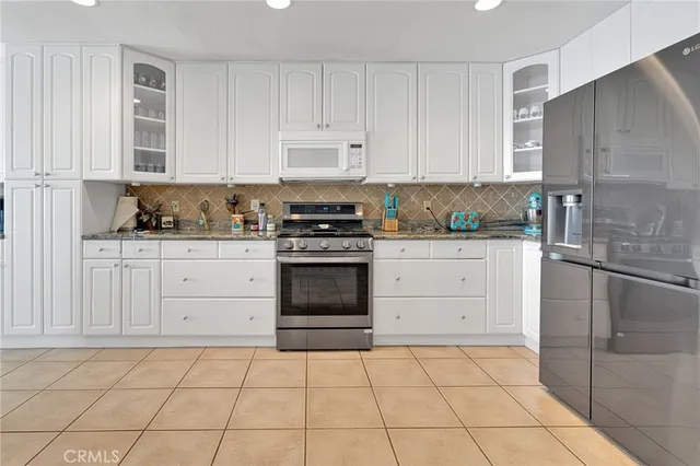 a kitchen with granite countertop a stove a sink and a refrigerator