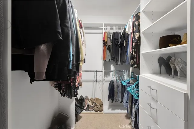 a view of walk in closet with clothes and shoes