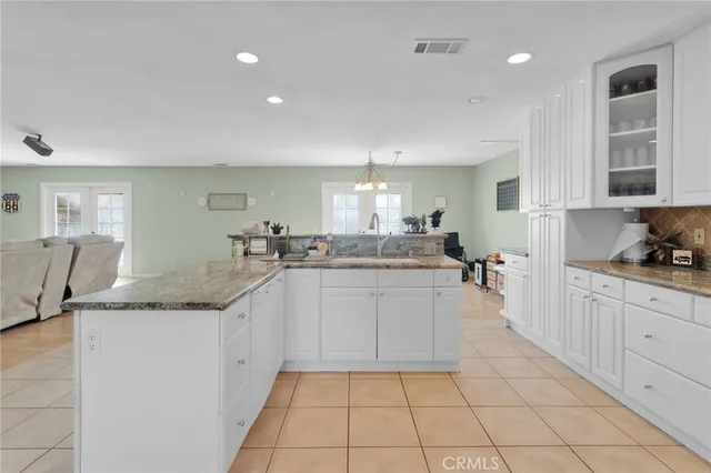 a large kitchen with granite countertop a sink and white cabinets